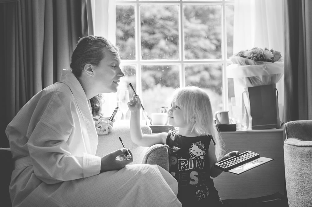 Flower girl helping bride put her make up on