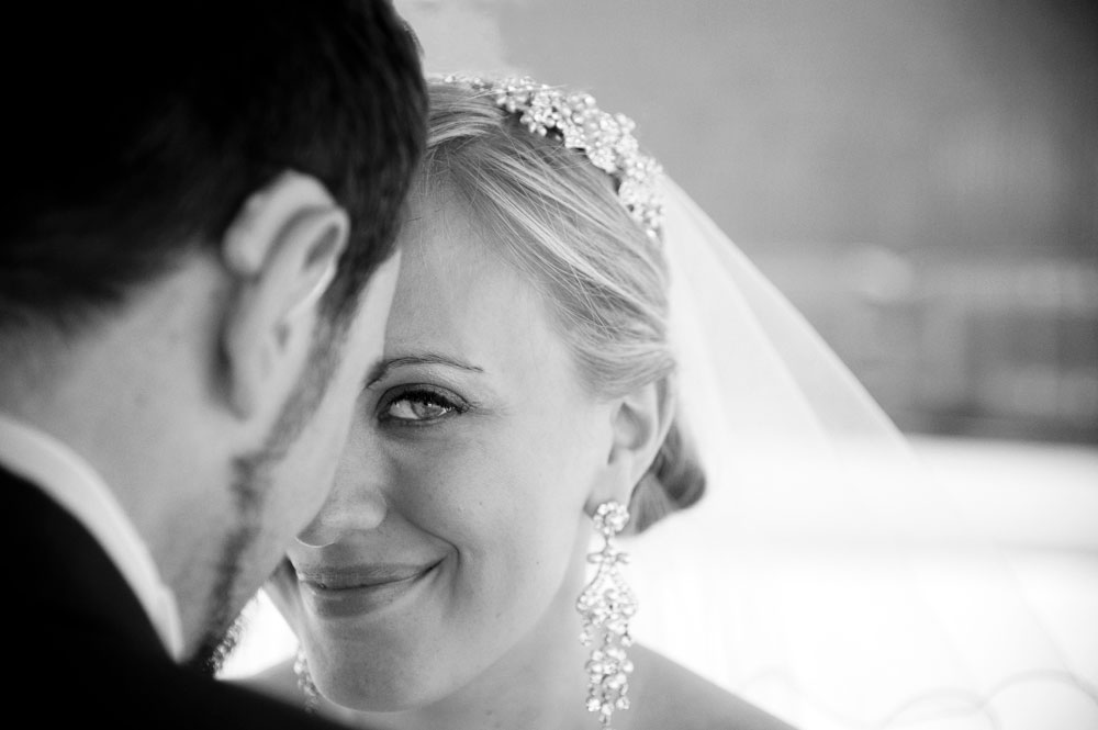 Bride looking at camera over groom’s shoulder