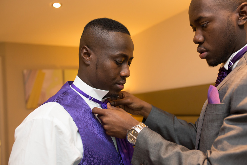 Groomsman fixing groom&rsquo;s tie