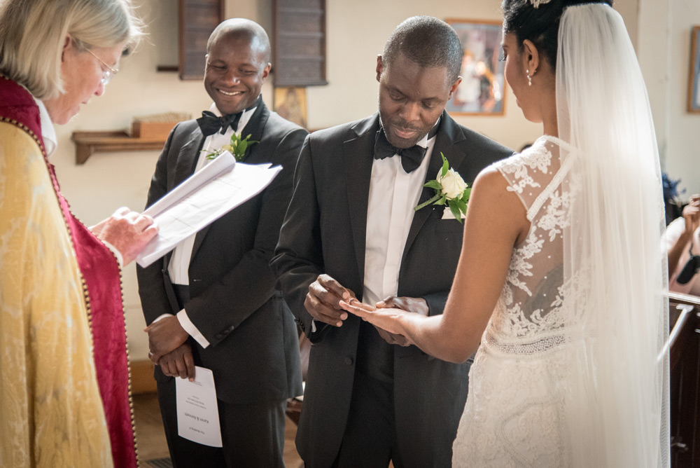 Groom putting ring on bride&rsquo;s hand