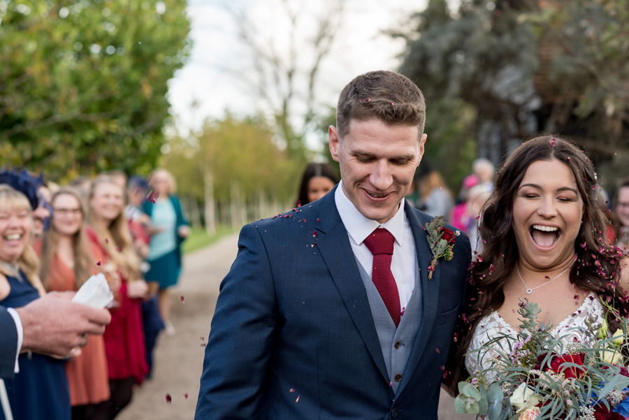Bride and groom walking while being showered with confetti