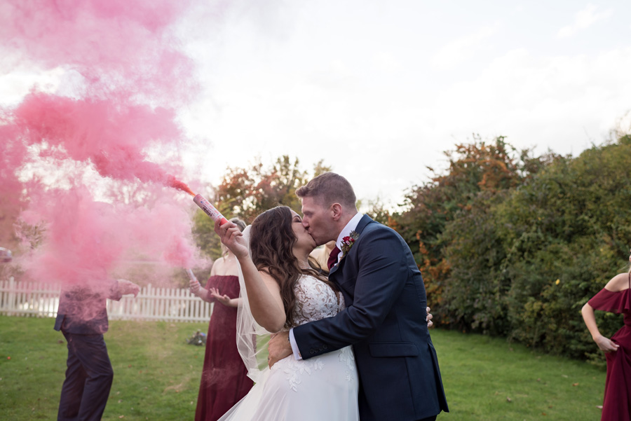 Bride and groom kissing with smoke bomb