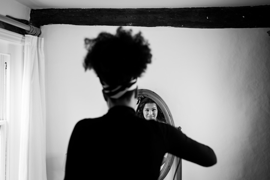 Black and white photo of bride in the mirror getting her hair done
