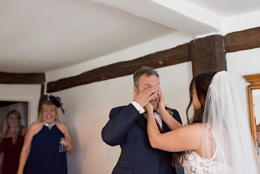 Father of bride wiping a tear away and bride comforting him