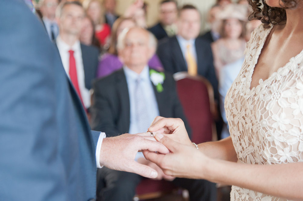 Bride putting wedding ring on groom&rsquo;s finger