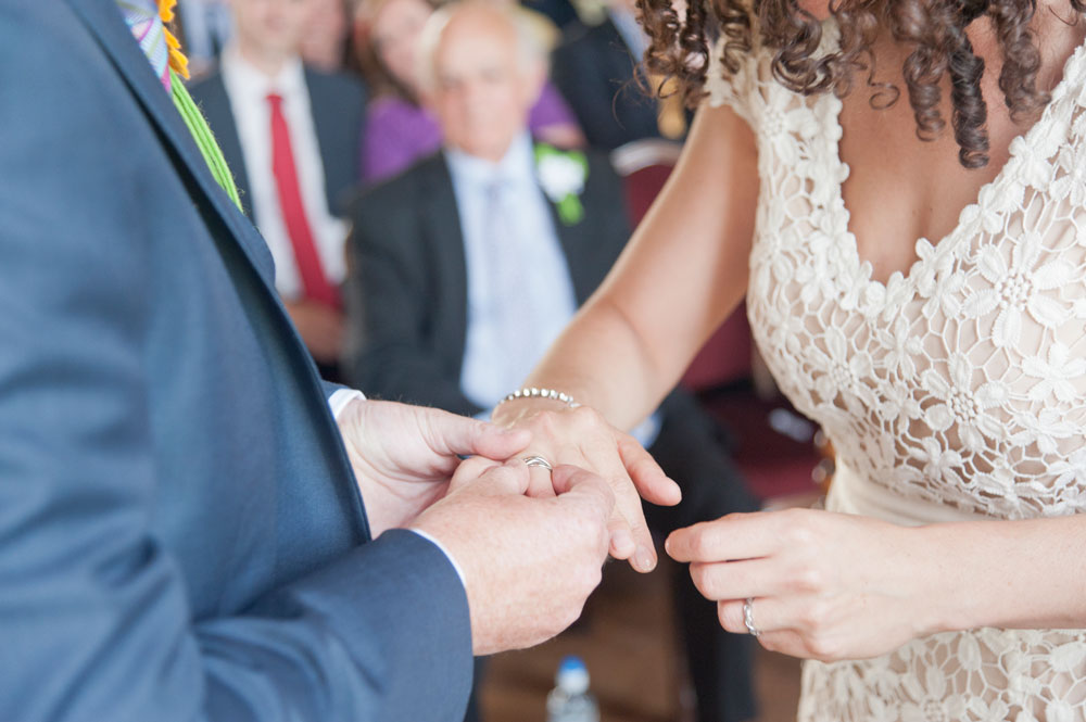 Groom putting ring on bride&rsquo;s finger
