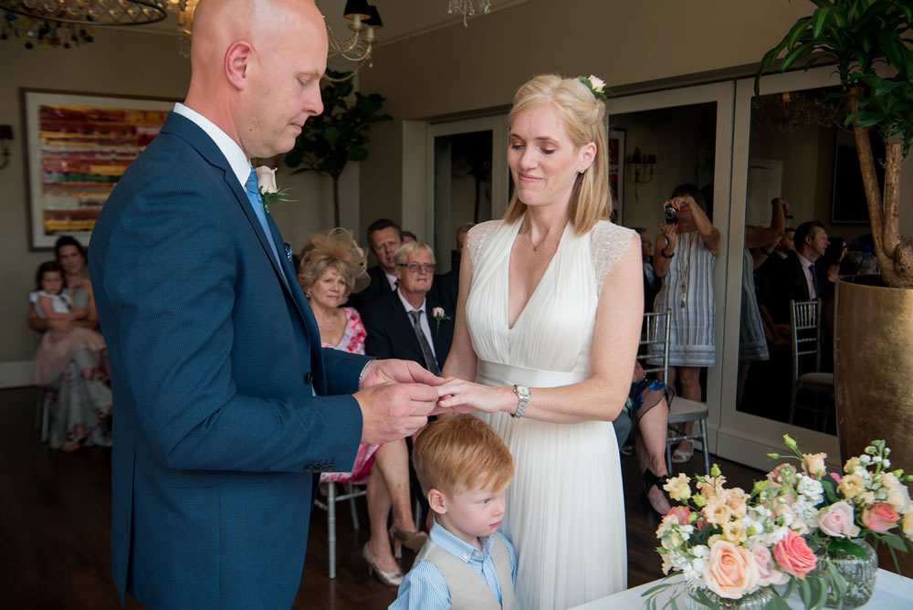 Groom putting ring on bride’s finger