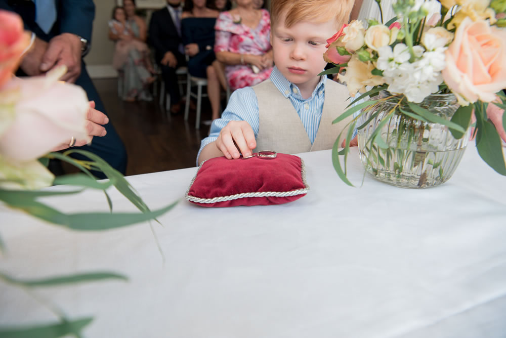 Page boy putting wedding rings on cushion