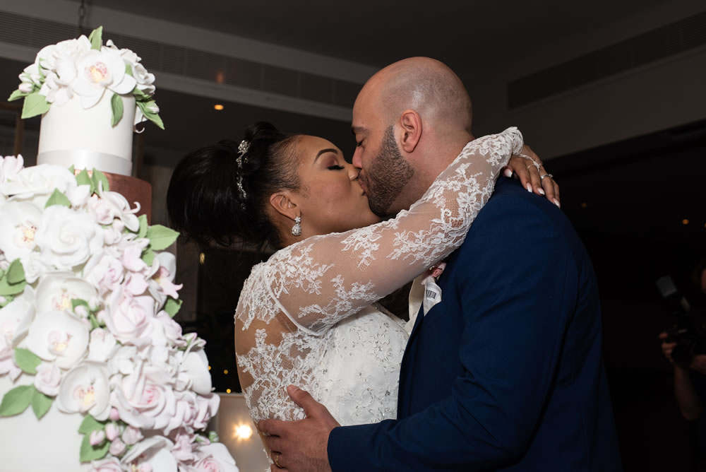 &ldquo;Couple kissing after cutting wedding cake