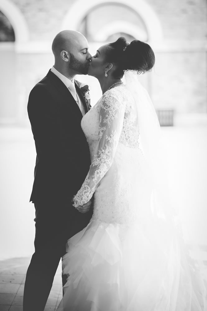 B&W of couple kissing while holding hands