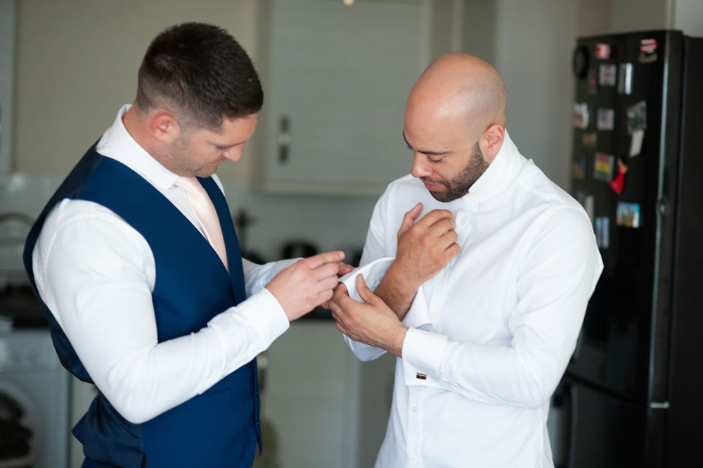 Best man helping groom with his cufflinks