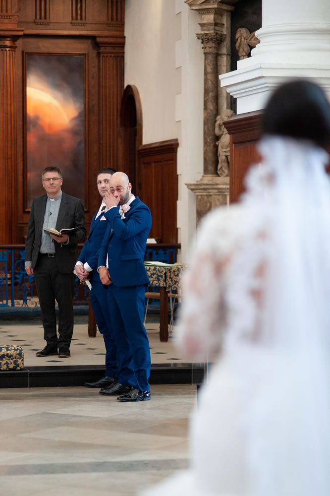 Groom watching bride walk down the aisle