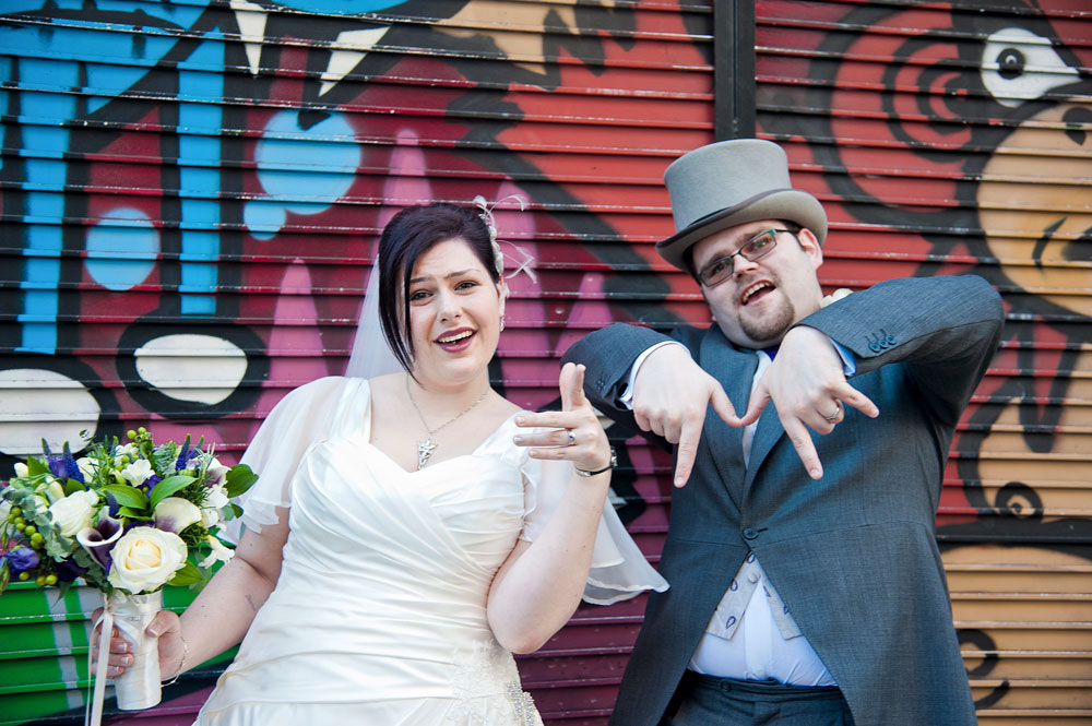 Couple goofing around in front of gaffitied shutters