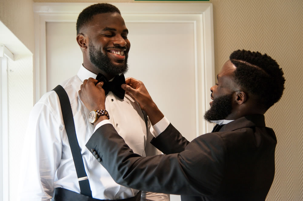 Groomsman fixing groom&rsquo;s bowtie