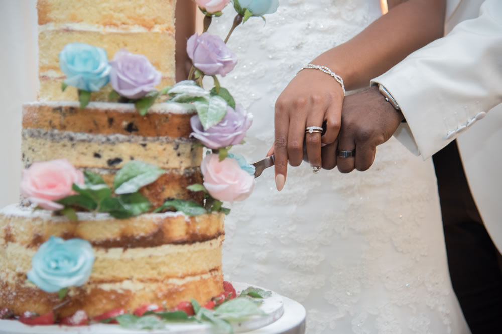 Couple&rsquo;s hands while cutting the cake